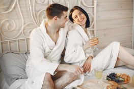 cute-couple-bedroom-wearing-bathrobes-having-breakfast_1157-46721